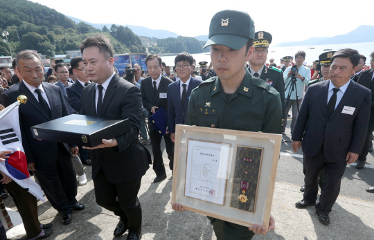8일 오후 경남 거제시 동부면에서 열린 고 김기봉 이등중사의 '호국의 영웅 귀환 행사'에서 군 관계자들이 유품 등을 들고 고인 아들 집으로 들어서고 있다.   연합뉴스